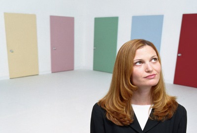 Woman in front of six doors unable to decide which door to use, illustrating analysis paralysis.