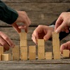 People placing building blocks in a stack signifying the art of trying to balance end-user needs.