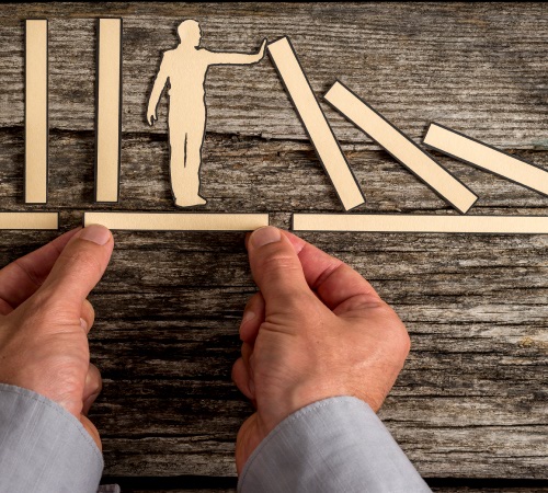 Image of person on a bookshelf holding back books from falling over depicting the need to control rogue projects.