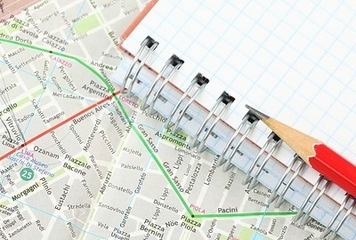 Image of city map and a graph pad and pencil noting the decision making process.