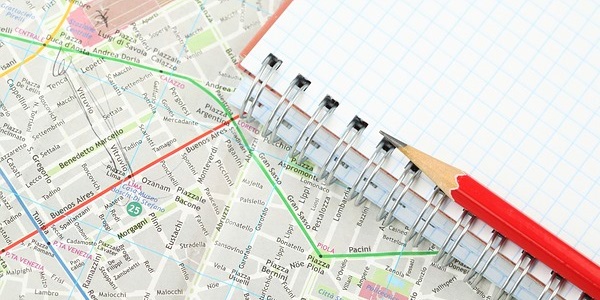 Image of city map and a graph pad and pencil noting the decision making process.