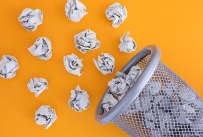 Crumpled papers near a trash can representing management mistakes.