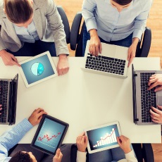 Team of people at table with computers signifying the need and use for a meeting agenda.