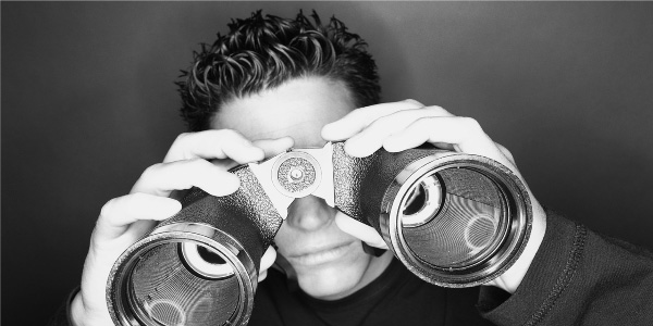 Image of man looking through binoculars depicting the need to perform a post meeting assessment.