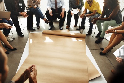 People sitting aroung a work table with plans to be reviewed working on team readiness.